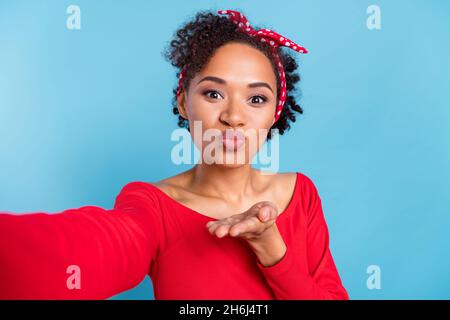 Photo de l'excitée flirty afro fille porter off-épaules rouge shirt enregistrement auto vidéo vous envoyer bras baiser sourire isolé couleur bleu arrière-plan Banque D'Images