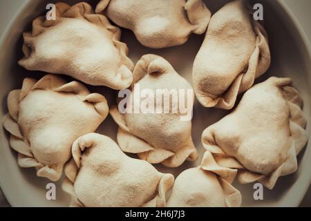 Vue de dessus de délicieux boulettes maison congelées qui se trouvent dans une grande assiette.Pâte avec divers garnitures à l'intérieur.Produits semi-finis congelés.Russe Banque D'Images