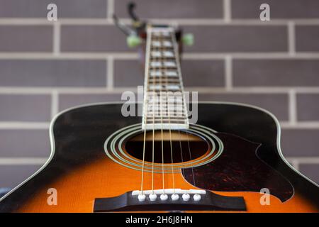 Guitare acoustique gros plan sur fond de mur de briques.Concentrez-vous sur le trou et les cordes sonores.Industrie musicale, faible profondeur de champ, concepts détaillés Banque D'Images