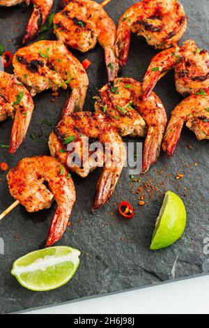 Piri Piri crevettes grillées sur les brochettes avec citron et condiment sur un plateau plat en bas photo Banque D'Images