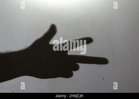 Flou, effet de flou, bruit, grain.Silhouette sombre d'une main montrant un geste des doigts.Contour de la main d'un homme avec trois doigts sur un bateau Banque D'Images