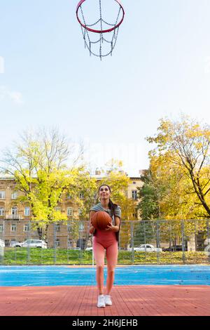 Une joueuse de basket-ball en saut jette le ballon dans le panier Banque D'Images