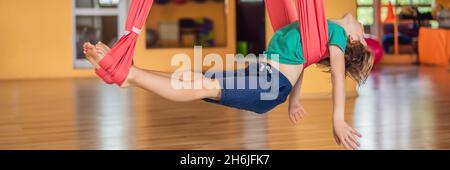 Jeune garçon pratiquant le yoga aérien dans la salle de sport.Style de vie.Bannière de yoga pour enfants, FORMAT LONG Banque D'Images