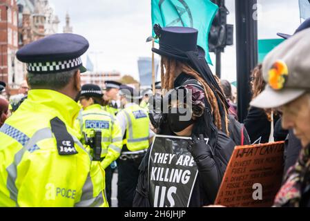 Femme vêtue de noir d'un écriteau « ils nous tuent » lors d'une manifestation contre Lord Mayor Show, Rise and Rebel march, extinction Rebellion, Londres, Royaume-Uni.13 novembre 2021 Banque D'Images