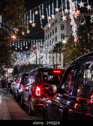 Une flotte de taxis à l'extérieur de Selfridges sur une rue très animée d'Oxford Street pendant la période de Noël. Banque D'Images