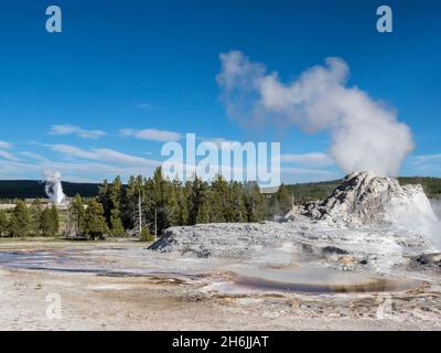 Château Geyser, avec éruption derrière Old Faithful, dans le parc national de Yellowstone, site classé au patrimoine mondial de l'UNESCO, Wyoming, États-Unis Banque D'Images