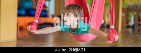 Jeune garçon pratiquant le yoga aérien dans la salle de sport.Style de vie.Bannière de yoga pour enfants, FORMAT LONG Banque D'Images