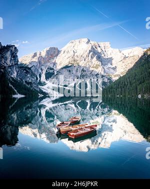 Bateaux amarrés dans le lac Braies (Pragser Wildsee) avec des montagnes reflétées dans l'eau au lever du soleil, Dolomites, Tyrol du Sud, Italie, Europe Banque D'Images