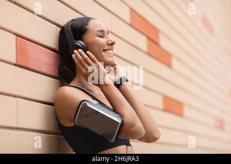 Liste de lecture favorite.Happy Sporty Young Lady porter un casque Ecouteurs écouter de la musique en plein air Banque D'Images