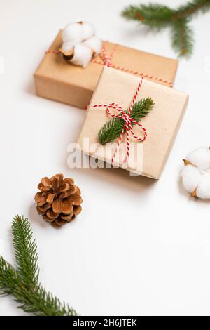 Deux boîtes-cadeaux surprise emballées dans du papier artisanal avec une branche d'épinette sur une table blanche.Arrière-plan des fêtes de Noël et du nouvel an Banque D'Images