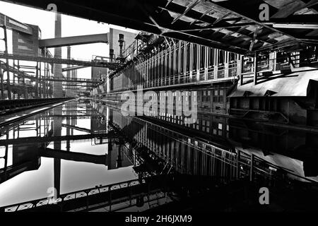 Allemagne, NRW, Essen, Zeche Zollverein; réflexions dans la surface de l'eau à côté de l'usine de cokéfaction. Banque D'Images