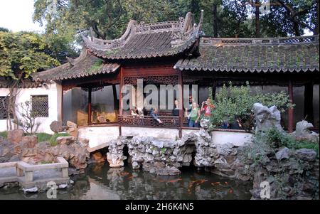 Jardins Yu Yuan, Shanghai, Chine: Les gens dans le jardin Yu regardant le poisson dans un petit étang.Yu Yuan est un jardin chinois traditionnel. Banque D'Images