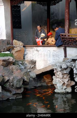 Jardins Yu Yuan, Shanghai, Chine: Les gens dans le jardin Yu regardant le poisson dans un petit étang.Yu Yuan est un jardin chinois traditionnel. Banque D'Images