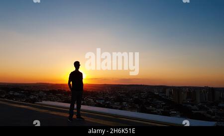 Silhouette d'un homme avec des lunettes sur le dessus d'un bâtiment. Banque D'Images