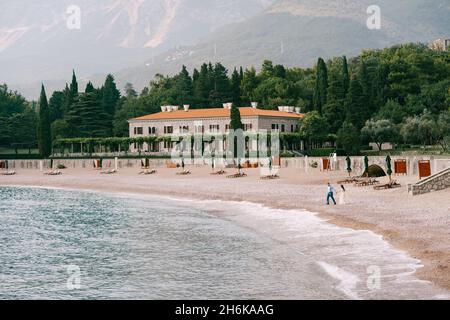 La mariée et la marche de marié tenant les mains sur le bord de mer de galets près de la belle villa Banque D'Images