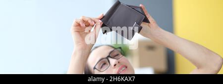 Jeune femme avec des lunettes, porte-monnaie vide à la maison Banque D'Images