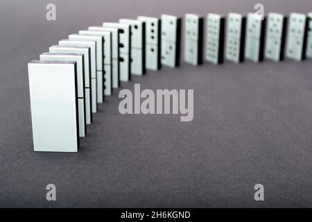 Dominos tombant en rangée, fond gris Banque D'Images