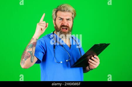 Médecin professionnel avec le presse-papiers pointant vers le haut du doigt.Un thérapeute sérieux avec stéthoscope tient le dossier.Antécédents médicaux et prescription. Banque D'Images