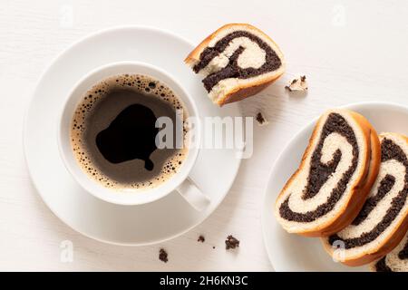 Tasse de café noir avec tranches de strudel de graines de pavot tchèque sur blanc.Vue de dessus. Banque D'Images