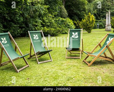 Chaises longues vertes traditionnelles attendant les visiteurs sur une pelouse verte avec le logo National Trust sur les pelouses de l'abbaye d'Anglesey près de la Lode Cambridge Banque D'Images