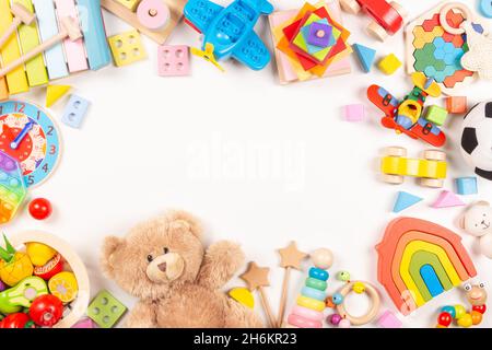 Cadre de jouets pour bébés enfants sur fond blanc.Ours en peluche et de nombreux jouets éducatifs en bois et en plastique.Vue de dessus, mise à plat, espace de copie pour le texte Banque D'Images