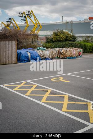 Recyclage du papier emballé dans un parking dans une zone industrielle avec des cueilleurs de cerises en arrière-plan et parking handicapés Banque D'Images