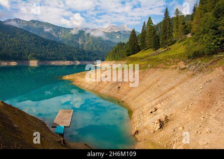 Faible niveau d'eau dans le lac Sauris, Italie, fin septembre.Le lac est artificiel, formé par un barrage.Les flotteurs bleus et la plate-forme sont normalement au niveau de l'herbe Banque D'Images