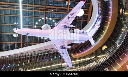 Vue de dessous sur le modèle d'avion blanc suspendu contre le beau plafond avec éclairage en forme d'objets de l'espace extérieur.Muse Banque D'Images