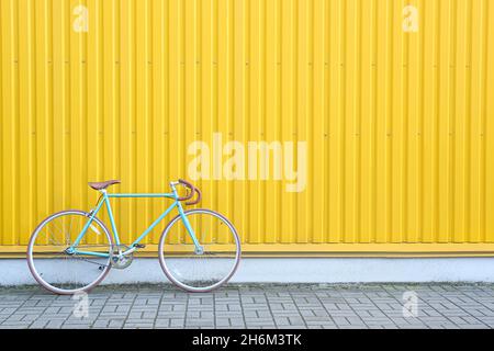Vélo bleu moderne près du mur jaune Banque D'Images
