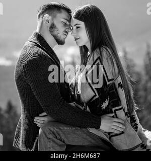 Couple aimant enveloppé dans une couverture assis sur la véranda d'une villa de montagne sur le fond des Carpates, vacances en famille. Banque D'Images