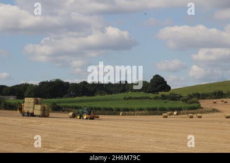 Des balles de foin rondes sont empilées sur un camion par un tracteur pour le transport hors du champ, le jour d'été près de Wakefield West Yorkshire, au Royaume-Uni Banque D'Images