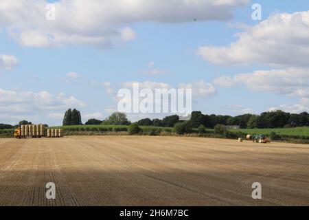 Des balles de foin rondes sont empilées sur un camion par un tracteur pour le transport hors du champ, le jour d'été près de Wakefield West Yorkshire, au Royaume-Uni Banque D'Images