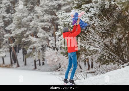 Petite fille souriante s'amusant avec son père dans un parc d'hiver.Mignon enfant de deux ans avec un parent jouant boule de neige maker jouet.Concept de famille heureuse et Banque D'Images