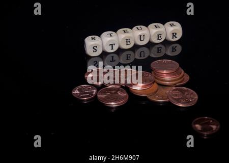 L'inscription sur les cubes, le mot TAXE en allemand sur les cubes de texture en bois avec des pièces de monnaie autour Banque D'Images