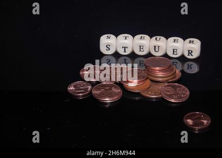 L'inscription sur les cubes, le mot TAXE en allemand sur les cubes de texture en bois avec des pièces de monnaie autour Banque D'Images