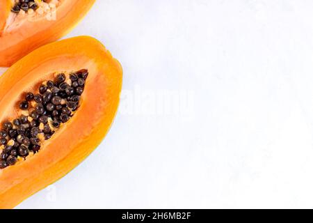 Fruits papaye exotiques orange vif coupés en deux tranches de graines noires sur fond clair avec espace de copie. Banque D'Images