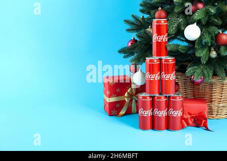 Odesses, Ukraine - 20 octobre 2021 : Composition arbre de Noël faite de canettes Coca-Cola et de boîtes-cadeaux, sur fond bleu Banque D'Images