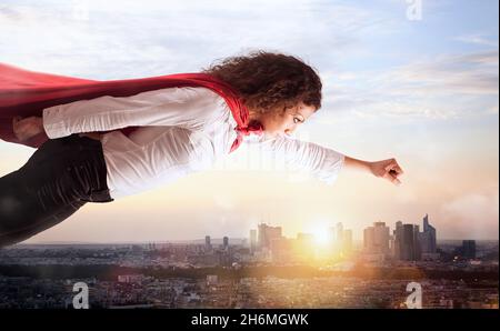 La femme agit comme un super-héros volant au-dessus de la ville Banque D'Images