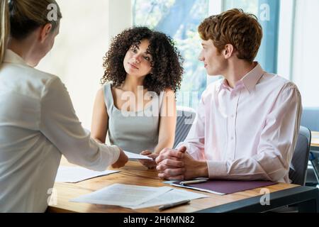 Jeune couple signant le contrat au bureau Banque D'Images