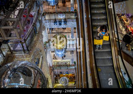 Une femme cashale sur l'escalator dans le grand magasin Selfridges à Oxford Street, Londres, Royaume-Uni à Noël entouré d'énormes décorations.Selfridges Banque D'Images