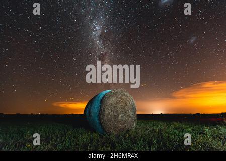 Vue panoramique de la balle de foin sur le terrain agricole contre la voie laiteuse dans le ciel Banque D'Images