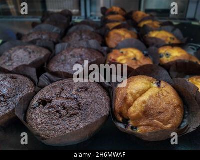 Muffins à la vanille et au chocolat en papier brun sur une vitrine de café-boutique, concept Banque D'Images