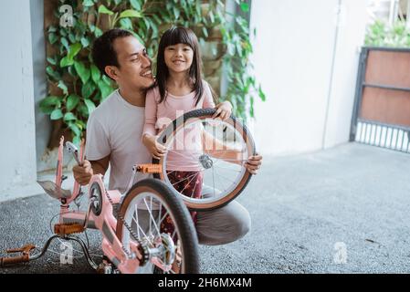 Père et fille souriant tout en portant une roue Banque D'Images