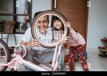 Père et fille souriant regardant la caméra entre les roues de vélo Banque D'Images