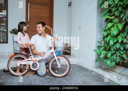 Fille discutant avec son père après avoir terminé l'assemblage de sa bicyclette Banque D'Images