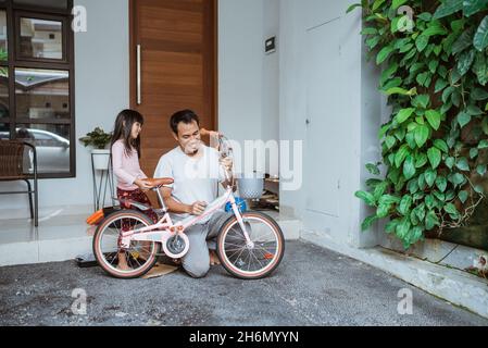 Fille et père tenant des bicyclettes après avoir terminé l'assemblage Banque D'Images