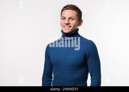 Photo de studio d'un jeune homme portant un chandail bleu à col roulé contre Banque D'Images