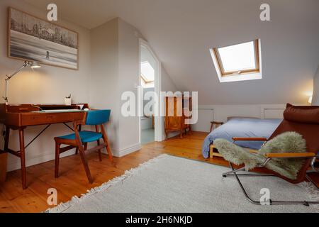 Cambridge, Angleterre - octobre 11 2019 : bureau de chambre de style loft avec parquet, bureau, fauteuil et lit. Banque D'Images