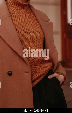 Coupe courte pour femme dans un manteau chaud d'automne marron et confortable et un pull en maille orange.Street décontracté mode. Banque D'Images