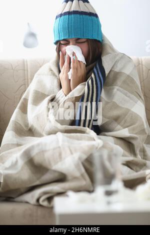 Femme malade soufflant le nez courant et éternuant dans les tissus à la maison Banque D'Images